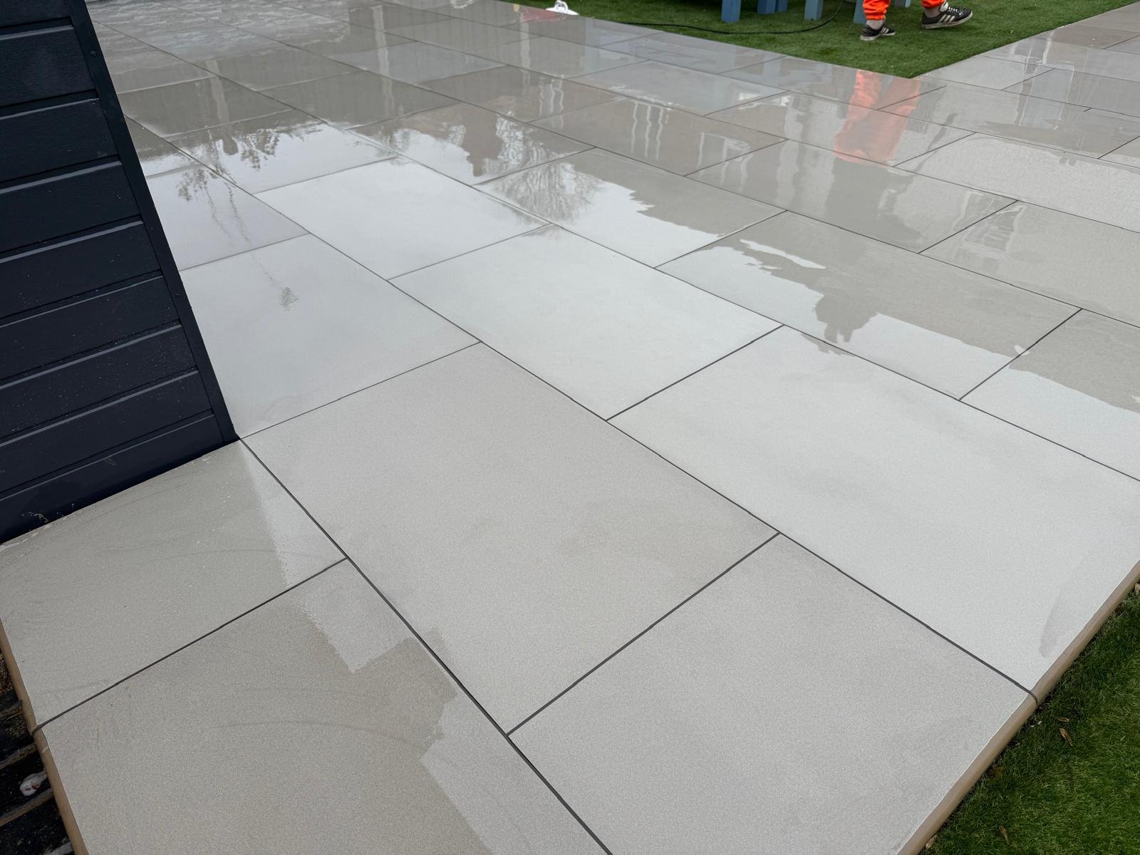 Pale patio slabs and a connecting garden path after rain