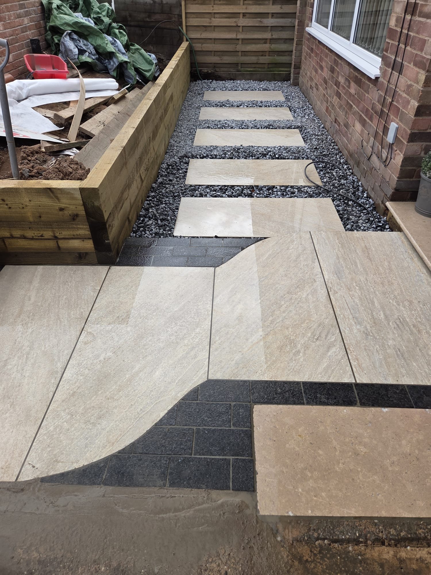 Pale stepping stones through dark gravel beside a raised timber bed