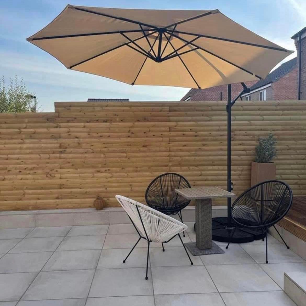 Timber privacy screen behind a paved seating area and parasol